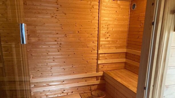 Een houten sauna met een bank en een klein bassin.