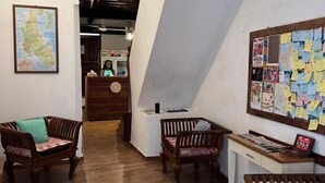 A spacious lobby with wooden flooring, a reception desk, and a bulletin board. - Stone Town House (Zanzibar Town)