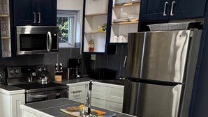 A modern kitchen with dark cabinets, stainless steel appliances, and a central island. - Cozy, comfortable 1-bedroom apartment in charming Eleuthera near to the beach. (North Eleuthera)