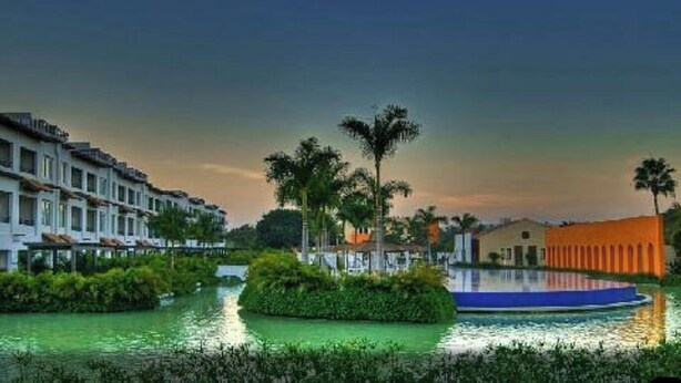 Ein Hotel am Wasser mit Pool, Palmen und einer Brücke.