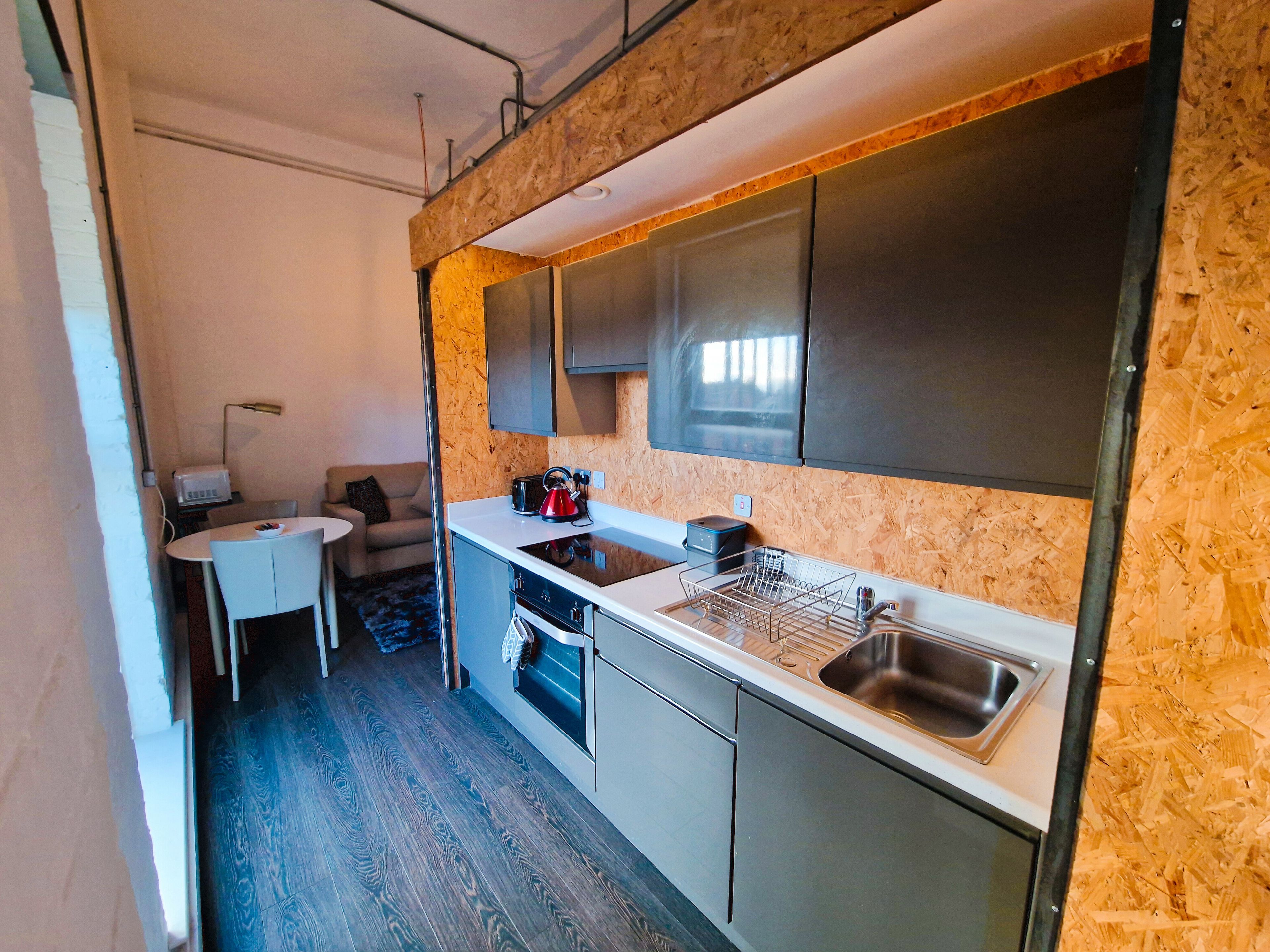 A compact kitchen with a built-in oven, a sink, and a microwave.