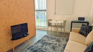 A modern living room with a flat-screen TV, a round dining table with chairs, a sofa, and a small table with a laptop. - Modern Stylish Apartment near the City Centre (Liverpool)