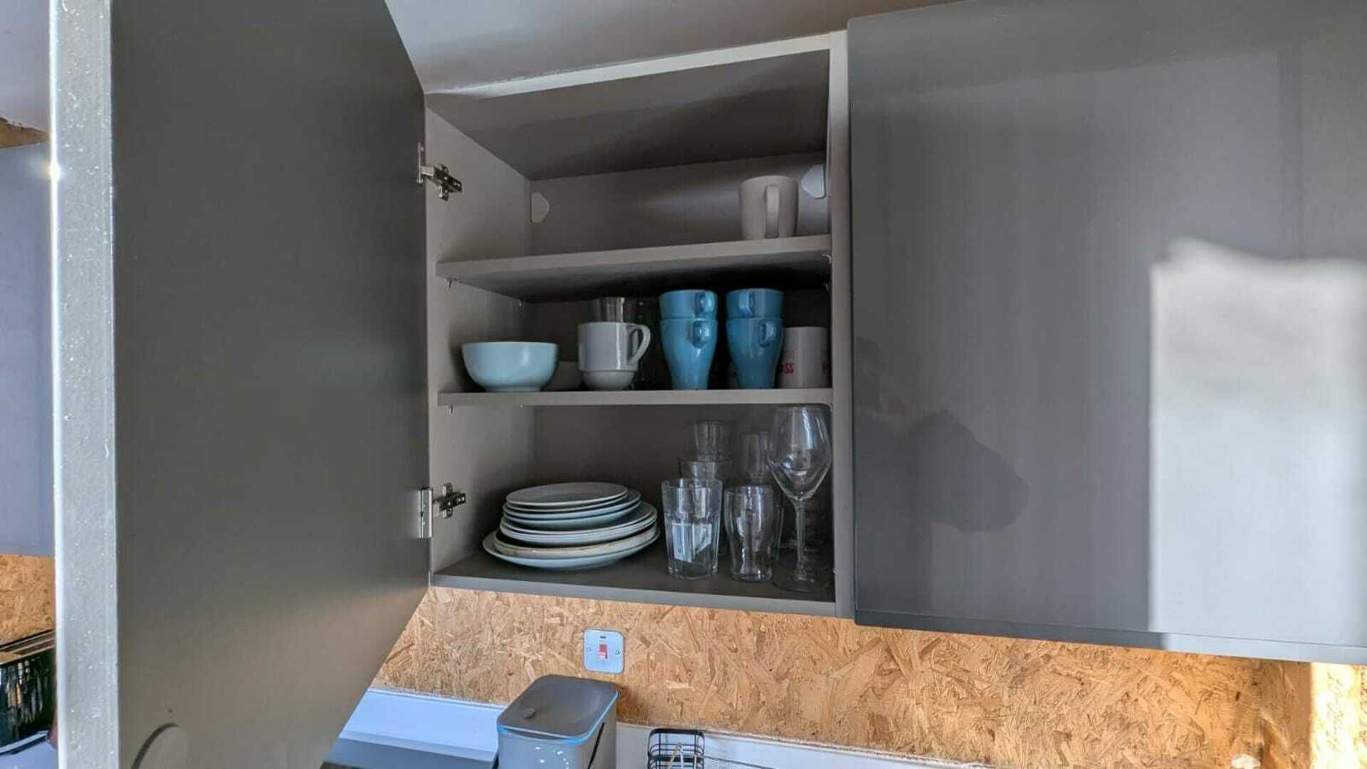 A kitchen with open cabinets displaying dishes and glasses.