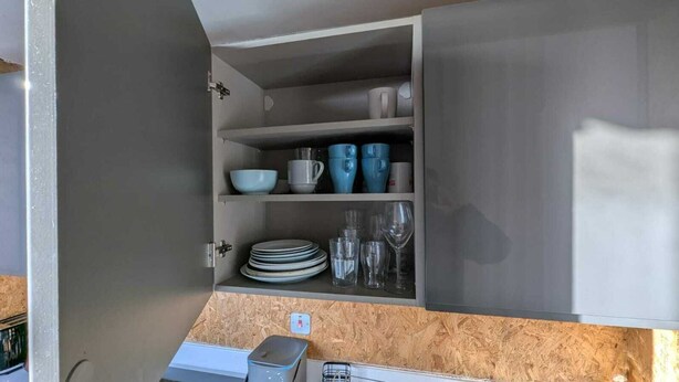 Une cuisine avec des placards ouverts où sont exposées la vaisselle et les verres.