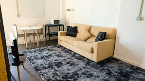 Un salon avec un canapé, une table basse, un téléviseur et une lampe.