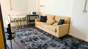 Ein Wohnzimmer mit Sofa, Couchtisch, Fernseher und Lampe.