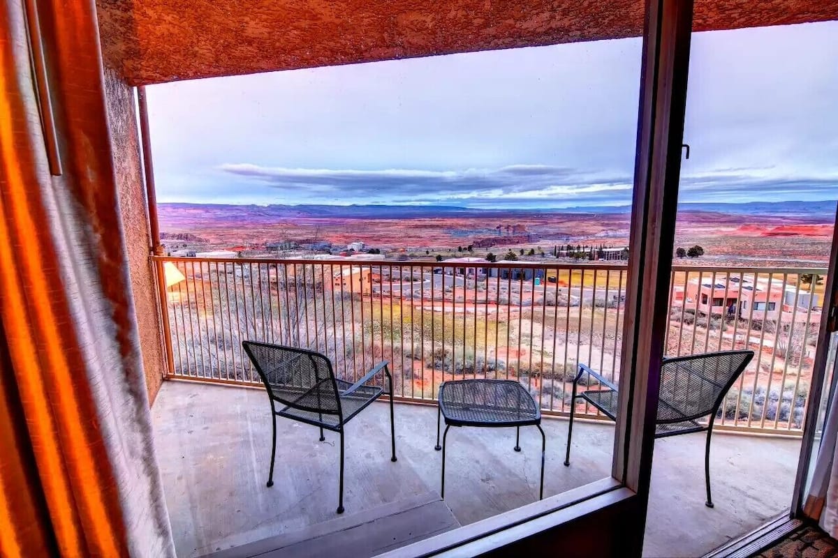 Un balcón con dos sillas de metal y vistas a un paisaje desértico.