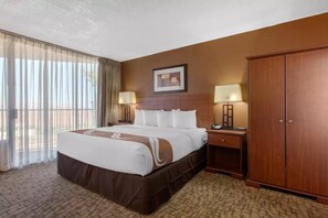 A hotel room with a large bed, two bedside tables with lamps, a wardrobe, and a framed picture on the wall. -  Scenic View Inn - Lake Powell - Page AZ (Page)