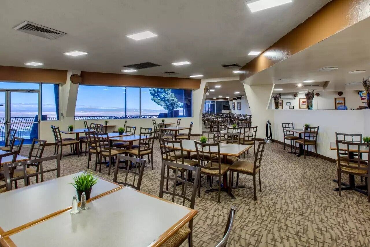 A restaurant with multiple tables and chairs, large windows with a view, and a carpeted floor.
