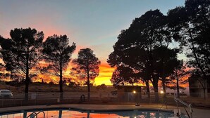 A swimming pool with a sunset view, surrounded by trees and a fence. -  Scenic View Inn - Lake Powell - Page AZ (Page)
