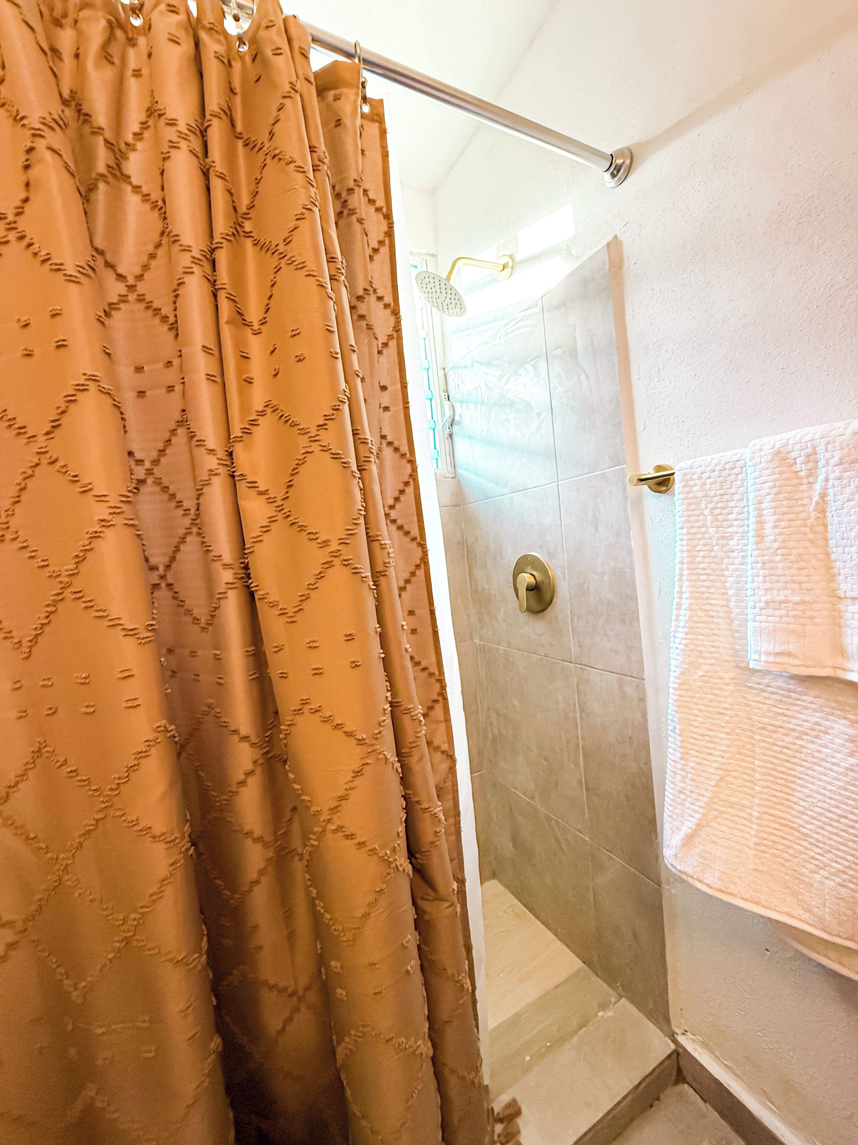 A bathroom with a shower, a towel rack, and a curtain.