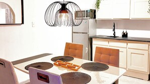 Een moderne eethoek met een witte tafel, vier stoelen en een bijzondere zwarte hanglamp.