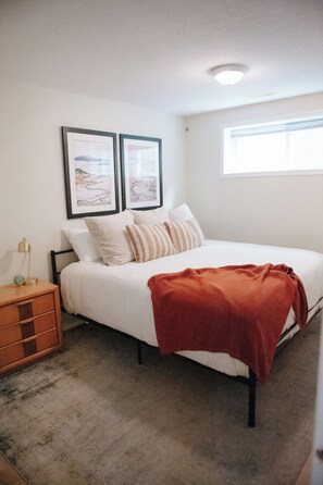 A bedroom with a bed, a nightstand, a dresser, and two framed pictures on the wall. - Stylish 3BR Retreat, Prime Local, Sleeps 8+Trundle (Lethbridge)