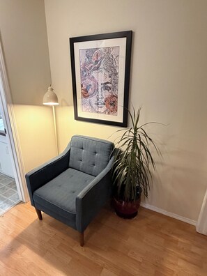A room with a grey armchair, a framed artwork on the wall, a floor lamp, and a potted plant. - Stylish 3BR Retreat, Prime Local, Sleeps 8+Trundle (Lethbridge)