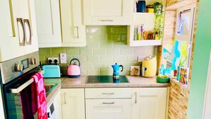 Een compacte keuken met lichte kastjes, een wasmachine, waterkoker en broodrooster.