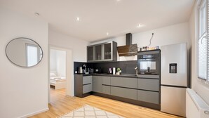 A modern kitchen with a built-in oven, refrigerator, and dark cabinetry.