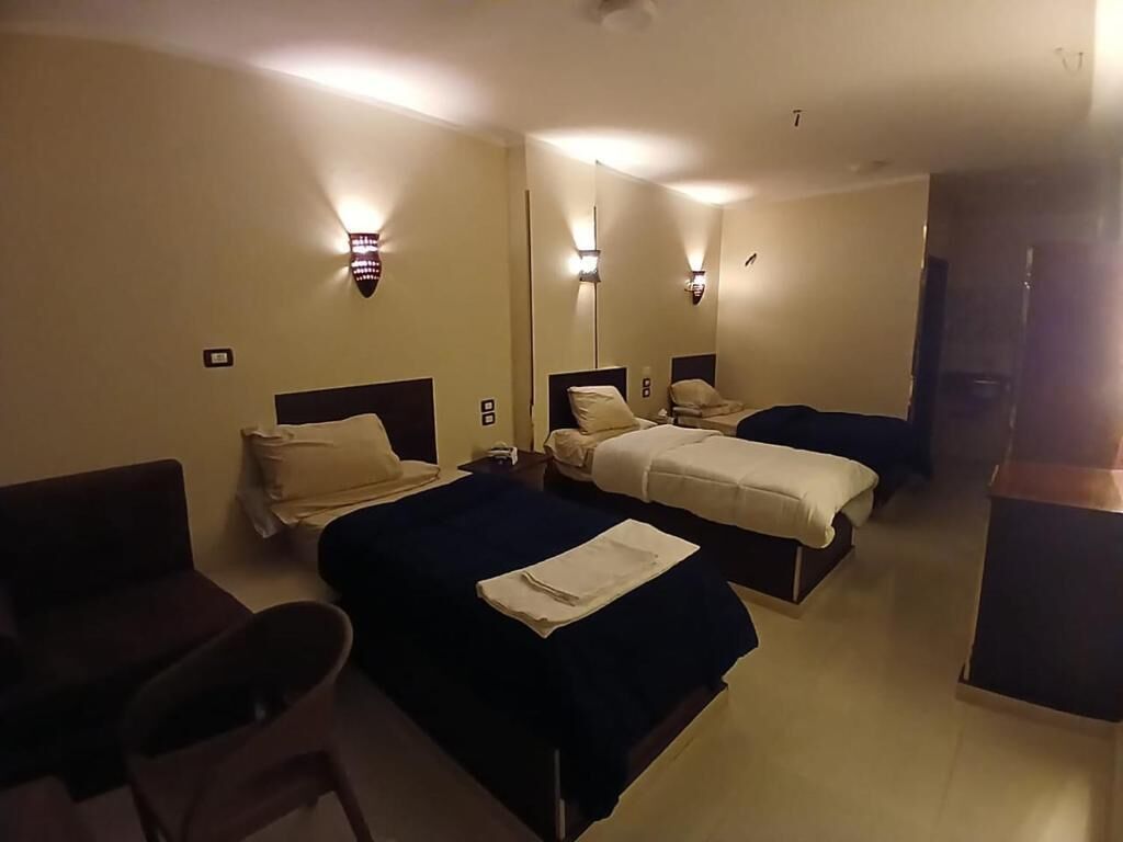 Habitación de hotel con dos camas, un escritorio y una silla.