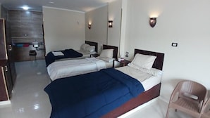 Una habitación de hotel con dos camas, una zona de estar, un espejo y una mesita.
