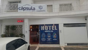Un hôtel avec une enseigne indiquant qu’il est ouvert 24 heures sur 24, un espace de stationnement et un numéro de téléphone à contacter.