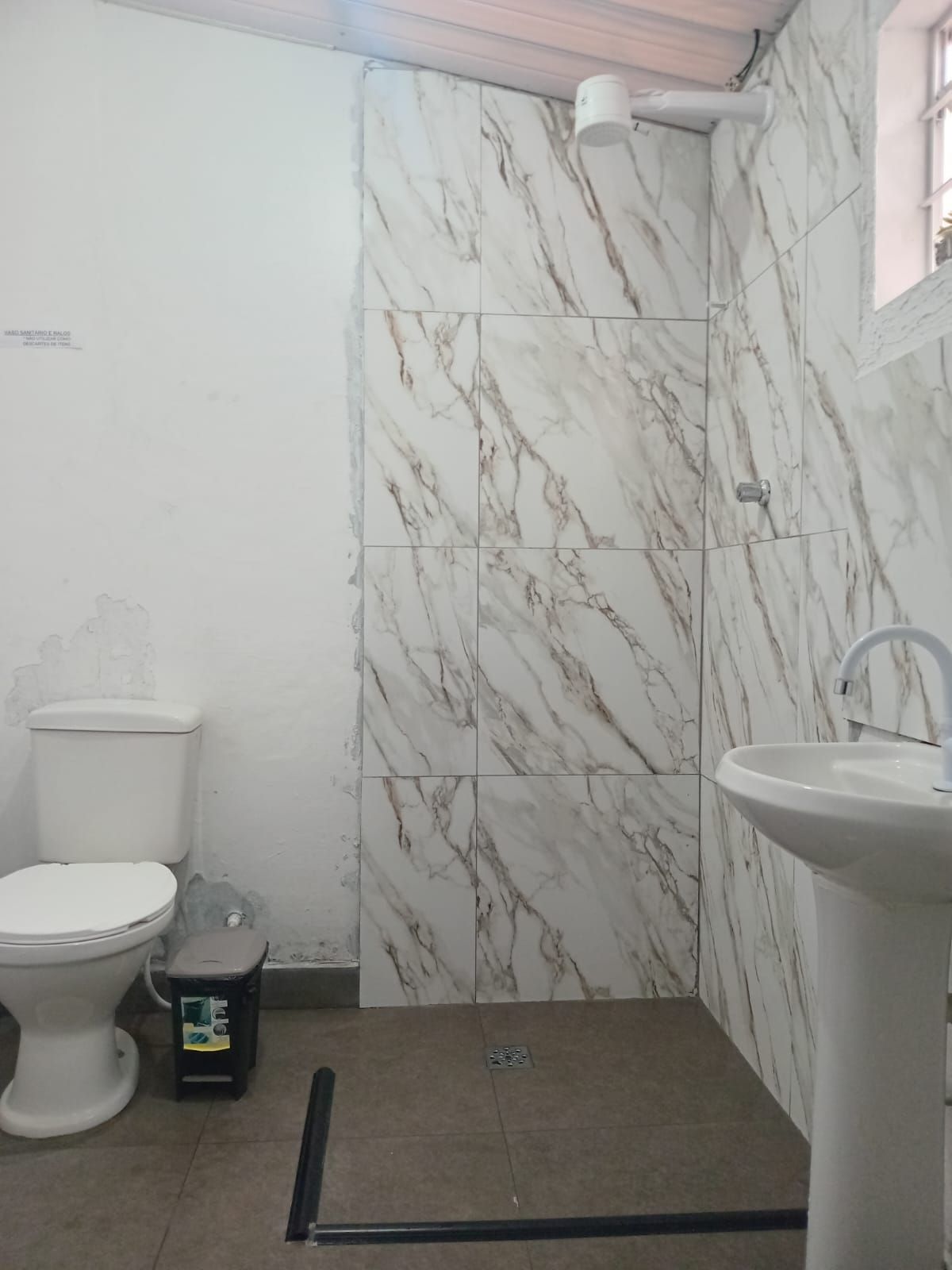 Un baño con inodoro, lavamanos y zona de ducha.