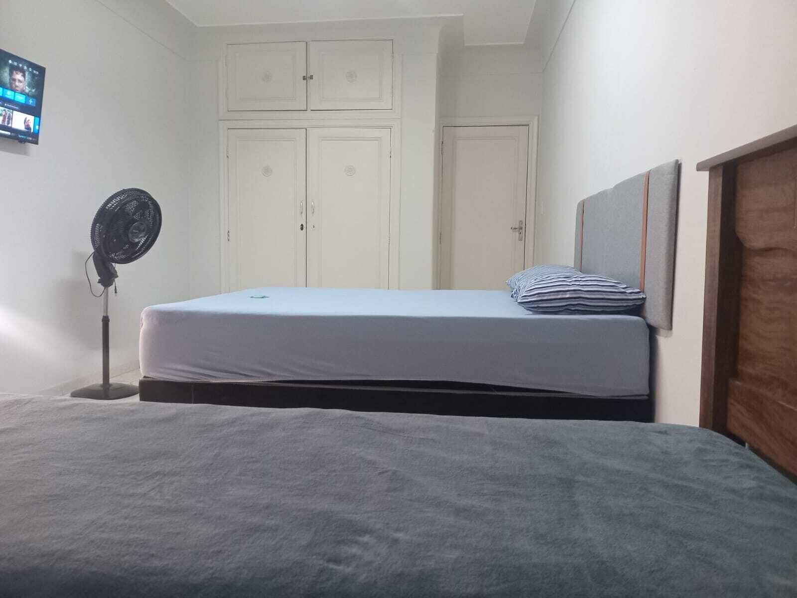 Un dormitorio con cama, ventilador y armario.