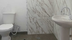 Une salle de bain comprenant des toilettes, un lavabo et un espace douche.