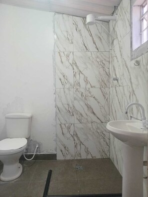 A bathroom with a toilet, sink, and shower area. - Capsula Residence Hotel (Marília)
