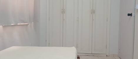 Une chambre à coucher avec un lit, une armoire et une porte.