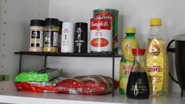 Una repisa de la despensa llena de diversos alimentos, como especias, conservas y salsas.