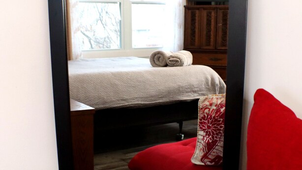 Une chambre à coucher avec un lit, une fenêtre, une armoire en bois et une chaise rouge.