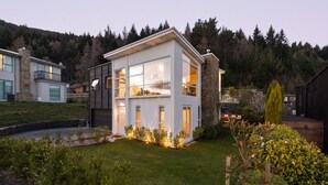 Ein modernes, zweistöckiges Haus mit gepflegtem Rasen und einem kleinen Teich.