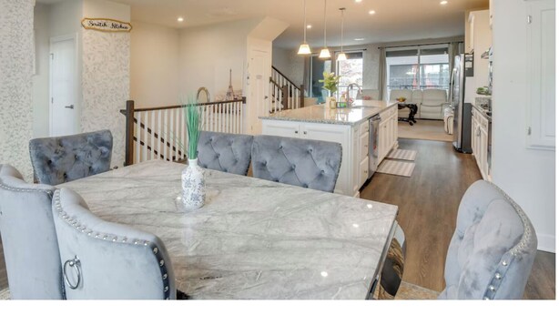 A spacious kitchen with a marble island, modern pendant lighting, and a view to the living area. - Delightful balti, Washington DC retreat (Laurel)