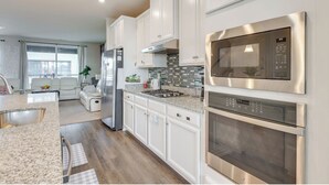 A modern kitchen with white cabinets, stainless steel appliances, and a granite countertop. - Delightful balti, Washington DC retreat (Laurel)