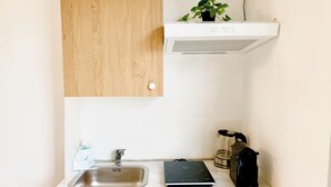 Une cuisine équipée d’un évier en acier inoxydable, d’une machine à café et d’une petite plante en pot posée sur le plan de travail.