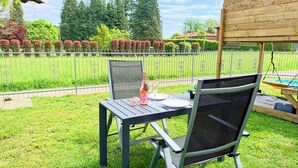 Une terrasse extérieure avec deux chaises et une table, une bouteille de Prosecco et un verre.
