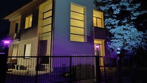 Un immeuble de deux étages, doté d’une façade sombre et de fenêtres illuminées.