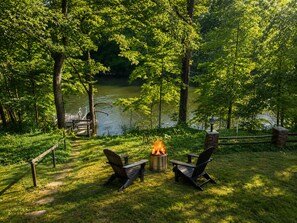 A lakeside outdoor seating area with two Adirondack chairs, a fire pit, and a dock. - The Lakeside Cove 4 Bed 3 Bath near Indiana Beach Full Kitchen Outdoor Firepit (Monticello)