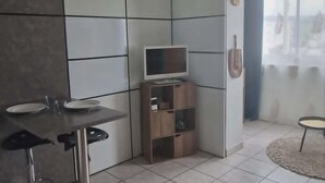 A modern kitchen with a dining area, a built-in TV, and a ceiling fan. - A little cocoon in the heart of Cantal (Arpajon-sur-Cère)