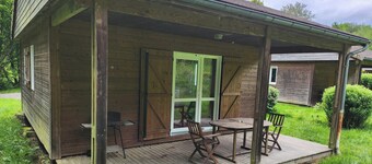 Cozy wooden chalets with terrace on forest edge facing a running stream.
