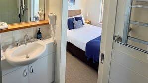 Camera d'albergo con bagno, un letto, un comodino e una finestra.