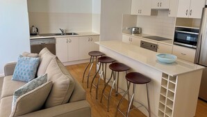 Una cucina moderna con mobili bianchi, un'isola centrale con sgabelli, forno integrato e microonde.