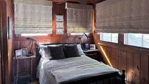 Un dormitorio de cabaña de madera con cama, escritorio y ventilador de techo.