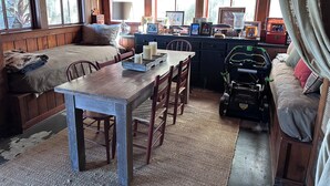 Interior acogedor de una cabaña con una mesa de madera, un banco y un sofá.
