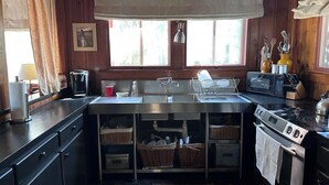 Una cocina compacta con una isla central, un lavabo, una estufa y un ventanal con cortinas.