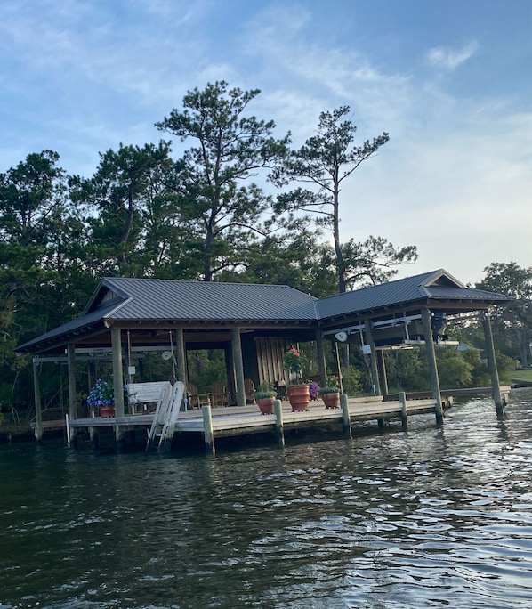 A wooden dock with a covered seating area and potted plants.
