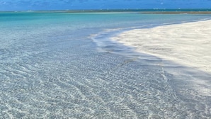 A beach with clear turquoise water and a sandy shore.