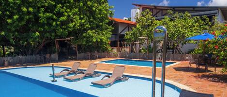 A swimming pool with lounge chairs and a diving board.