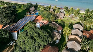A resort with a swimming pool, thatched-roof structures, and a view of the ocean.