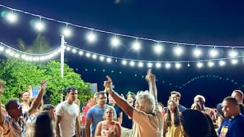 Un grupo de personas bailando al aire libre por la noche bajo luces colgantes.