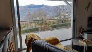 A room with a large sliding glass door leading to a balcony with a view of mountains and a fence. - Mountain house 8 persons 4 épis with Sauna (Arcizans-Avant)